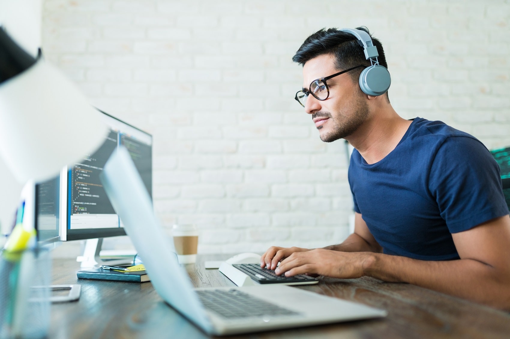 Software developer programming at desk, wearing headphones